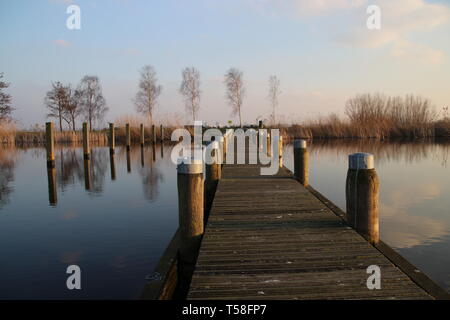 Pier at the Rottemeren colored by the sunlight during sunset in Zevenhuizen Stock Photo