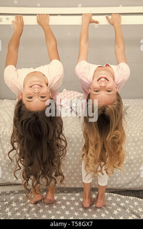 Little girls with long blond hair hang upside down. Hair salon for kids. Stock Photo