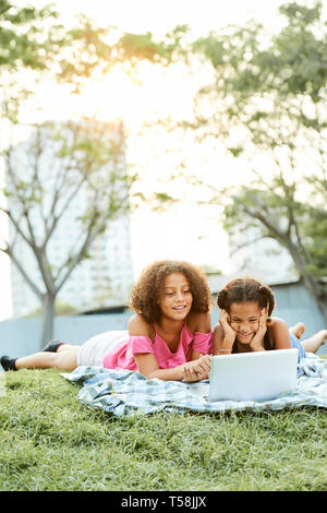 Happy school friends using laptop in park Stock Photo