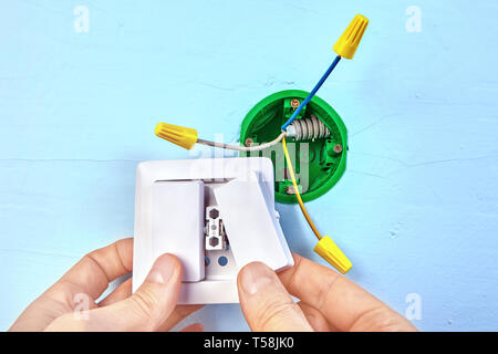 Electrician is installing european standart socket box, electric installation work. Double switch placed in the socket. Stock Photo
