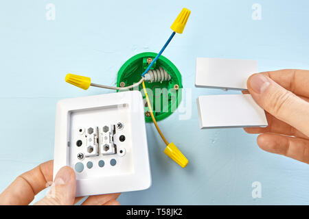 Installation of new button for two-button light switch, round outlet box for wall light on the background. Stock Photo