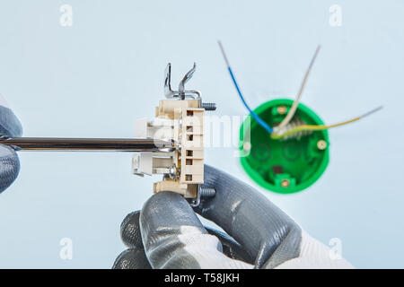 Twisting screw in new double light switch by electrician with screwdriver, electrical work. Stock Photo