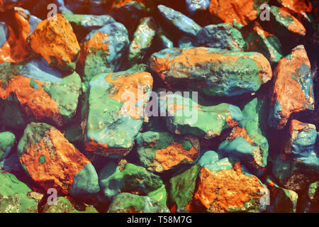 closeup stone drenched in orange, blue and green paint Stock Photo