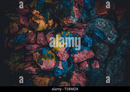 dark abstract background of stones covered with multi-colored paint Stock Photo