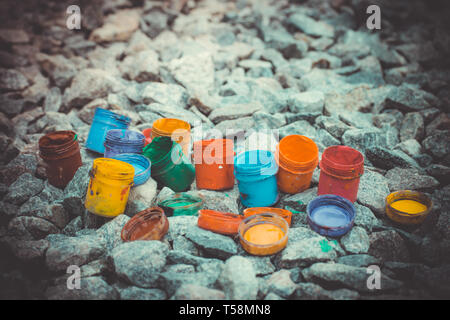jar from under the paint of different colors on the gray stones, filter close-up Stock Photo