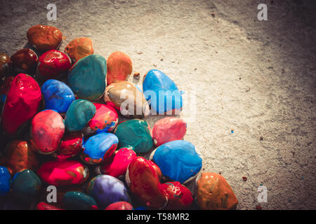 Colored stones colored paints in different colors lie on a flat surface. Second half empty. Close-up Stock Photo