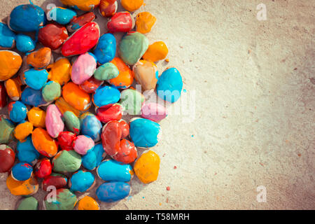 Colored stones colored paints in different colors lie on a flat surface. Second half empty. Close-up Stock Photo
