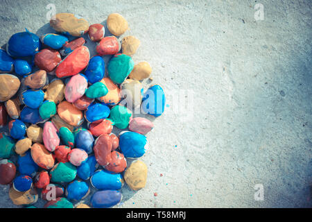 Colored stones colored paints in different colors lie on a flat surface. Second half empty. Close-up Stock Photo