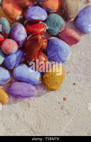 Colored stones colored paints in different colors lie on a flat surface. Second half empty. Close-up Stock Photo