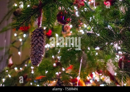 Pine cone ornament with white string lights on a christmas tree in the winter Stock Photo