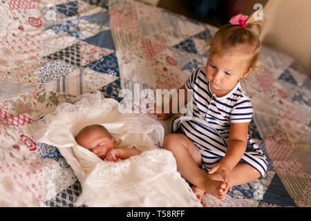 Newborn baby boy in bed. Cute toddler girl playing with her newborn baby brother. Stock Photo