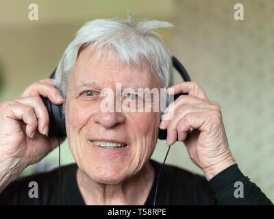 Portrait of a senior man using headphones for listening music with a happy look on his face Stock Photo