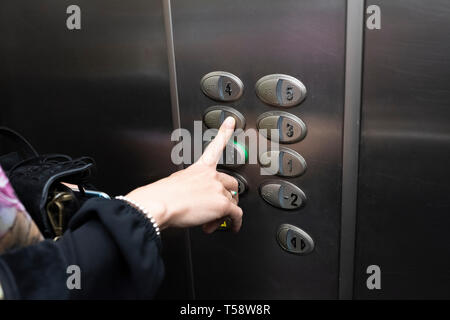 woman inside an elevator pressing a button Stock Photo