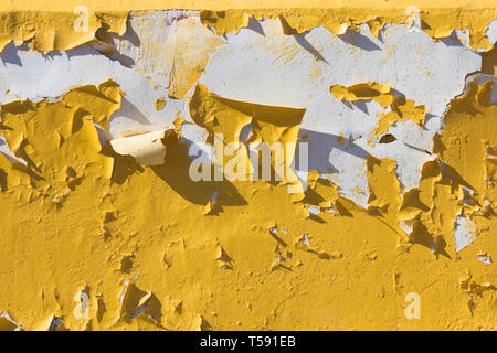 Yellow peeling paint from the wall. Texture paint cracks. Yellow paint. Old wall Stock Photo