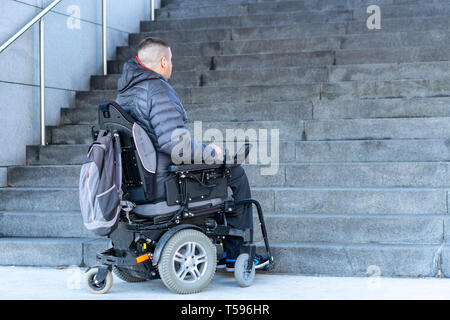 young disabled man in a electric wheelchair in front of stairs Stock Photo