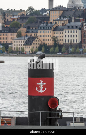 The distinctive black and red funnel of the Djurgården ferry with the colourful buildings of Södermalm in the background Stock Photo