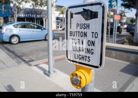 Manhattan Beach, California - March 26, 2019: Sign instructs pedestrians to push button to turn on the warning lights for cars, to all people to cross Stock Photo