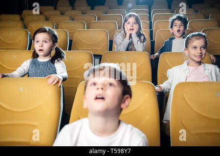 surprised multicultural friends watching movie in cinema together Stock Photo