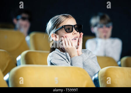 selective focus of worried child in 3d glasses holding hands on face while watching movie