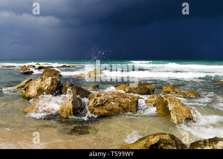 Splashing surf, stones in water against stormy sky Stock Photo