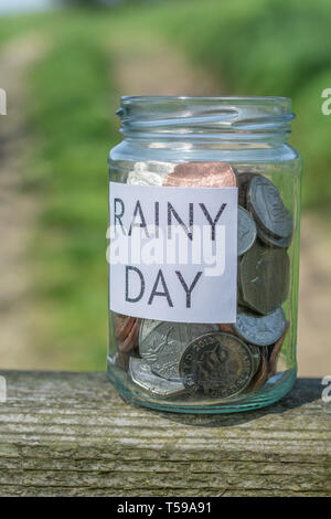 Money jar / rainy day savings jar outdoors in sunshine. Metaphor personal savings, saving money, retirement savings, saving for retirement, saving pot Stock Photo