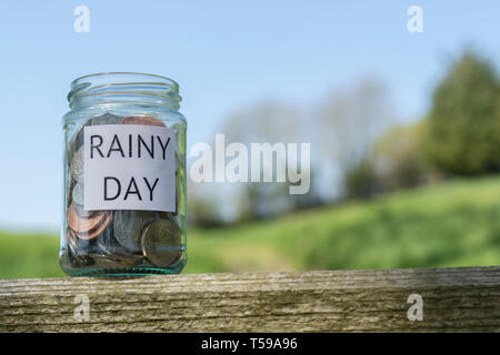 Money jar / rainy day savings jar outdoors in sunshine. Metaphor personal savings, saving money, retirement savings, saving for retirement, saving pot Stock Photo