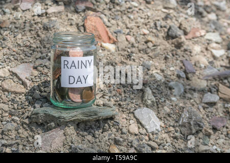 Money jar / rainy day savings jar outdoors in sunshine. Metaphor personal savings, saving money, retirement savings, saving for retirement, saving pot Stock Photo