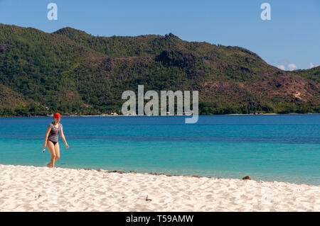 a tourist woman walking on the desert white beach of the island of Curieuse. Seychelles Stock Photo