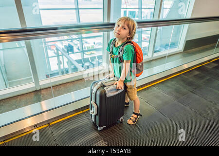 Funny little boy going on vacations trip with suitcase at airport, indoors Stock Photo