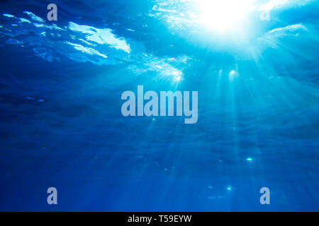 Underwater shot with sunrays in deep blue tropical sea Stock Photo