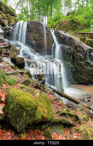 beautiful waterfall in the beech forest. huge mossy wet rocks. wonderful nature background. long exposure Stock Photo