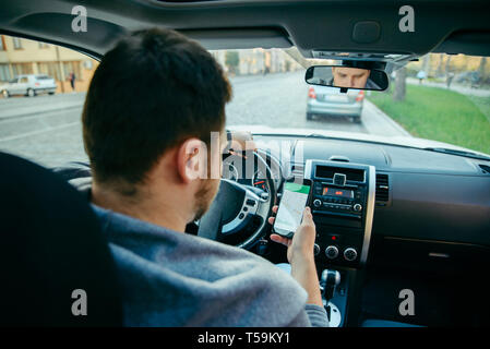 man hands on steering wheel using phone as navigator. road trip Stock Photo
