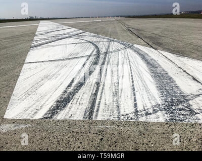 The rubber tracks from the rallye or racing cars left on the tarmac on the old airfield. You can see the tracks on the big white X marking. Stock Photo