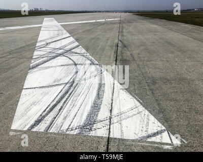 The rubber tracks from the rallye or racing cars left on the tarmac on the old airfield. You can see the tracks on the big white X marking. Stock Photo