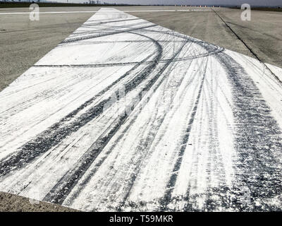 The rubber tracks from the rallye or racing cars left on the tarmac on the old airfield. You can see the tracks on the big white X marking. Stock Photo