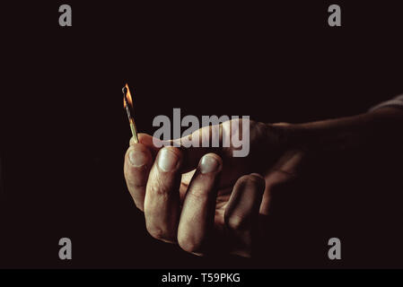 Burning match in the man's hand. Dangerous game with fire. Stock Photo