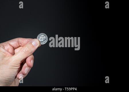 Male hand holding a five pence coin with the image of Elizabeth II, isolated over black, brexit concept. Stock Photo