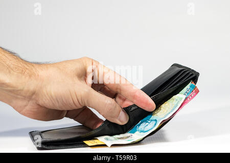 A male hand opening a leather wallet showing a five pound polymer from UK. Stock Photo