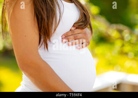 Mid-section of pregnant woman standing outdoor holding hands on belly Stock Photo