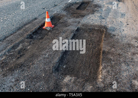 White orange traffic hazard cone on asphalt road repair Stock Photo