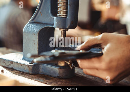 Man works in carpentry workshop. He fixes wooden handle in vice. Different tools are on workbench. Men at work. Hand work. Stock Photo