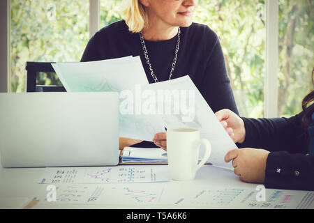 Closeup of two executive business women discussing and analyzing data result papers on desk Stock Photo