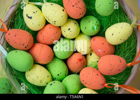 Green nest with colorful Easter eggs decoration on light purple background. Easter concept, holiday tradition top view, close-up image Stock Photo