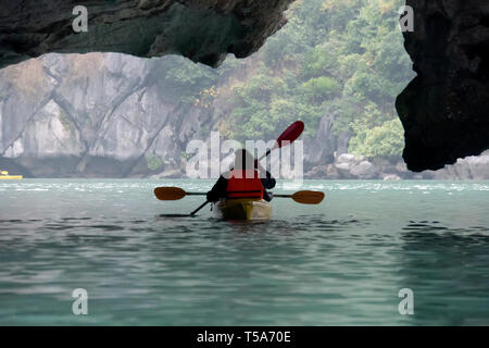 Couple exploring cave on karst kayak and taking photograps in the boat. Ha Long Bay, Vietnam, Cat Ba Island Stock Photo