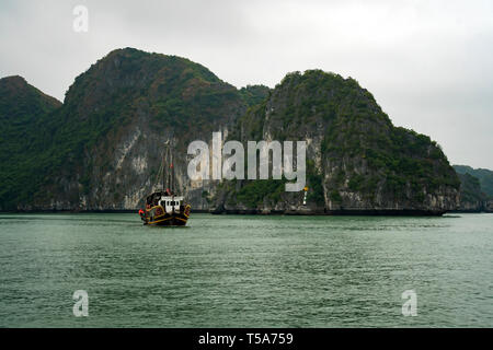 cruising among beautiful limestone rocks and secluded beaches in Ha Long bay, UNESCO world heritage site, Vietnam. Stock Photo