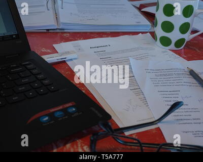 Assignment for an Open Polytechnic course on writing plain English, with question, course material, laptop and thumb drive, glasses, pencil, coffee. Stock Photo