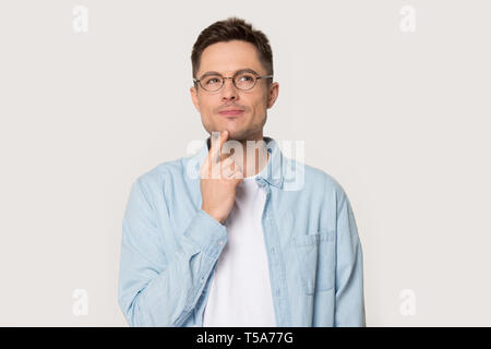 Thoughtful man in glasses isolated on grey background thinking Stock Photo