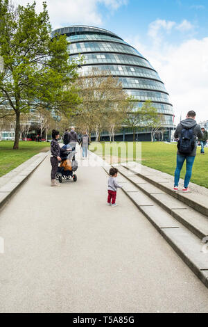 Tourists on the South Bank with City Hall building in the background in London. Stock Photo