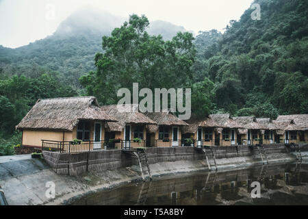 Abandoned houses of an old hotel in the woods. Straw, bamboo, thatch-roof cottage resort delivered in line with mountains as a backdrop. Stock Photo