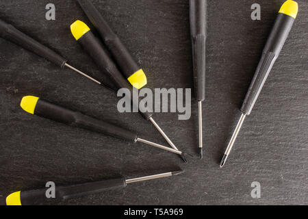 Lot of whole screwdrivers with a yellow black plastic handle work item flatlay on grey stone Stock Photo